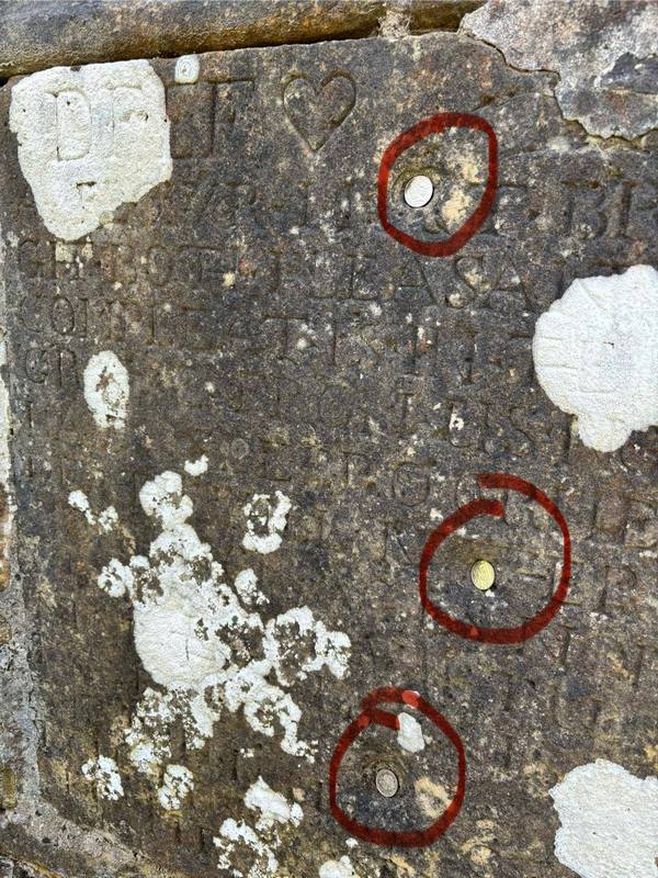 Musket ball holes in Boleskin Gravestone indicated with coins
