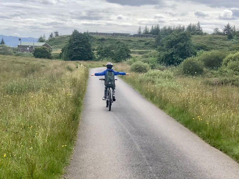 Child cycling hands free on quiet road on Isle of Eigg