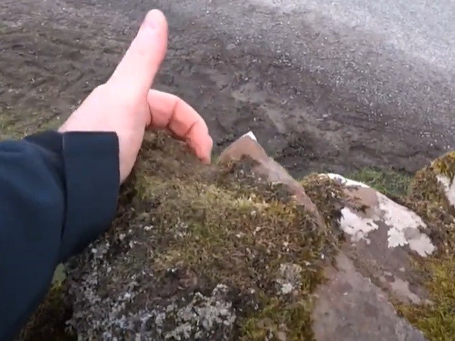 A photograph trying to indicate a groove in a coping stone that may have been used for sharpening sword blades.